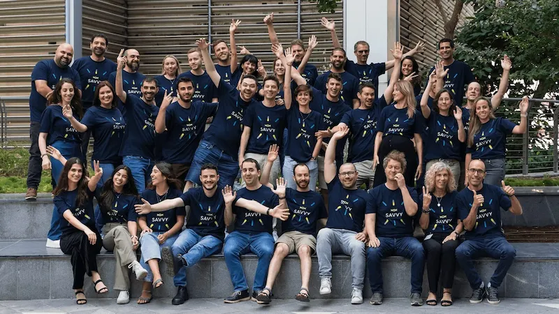 A group of people in matching shirts sitting and standing on steps, smiling and waving.